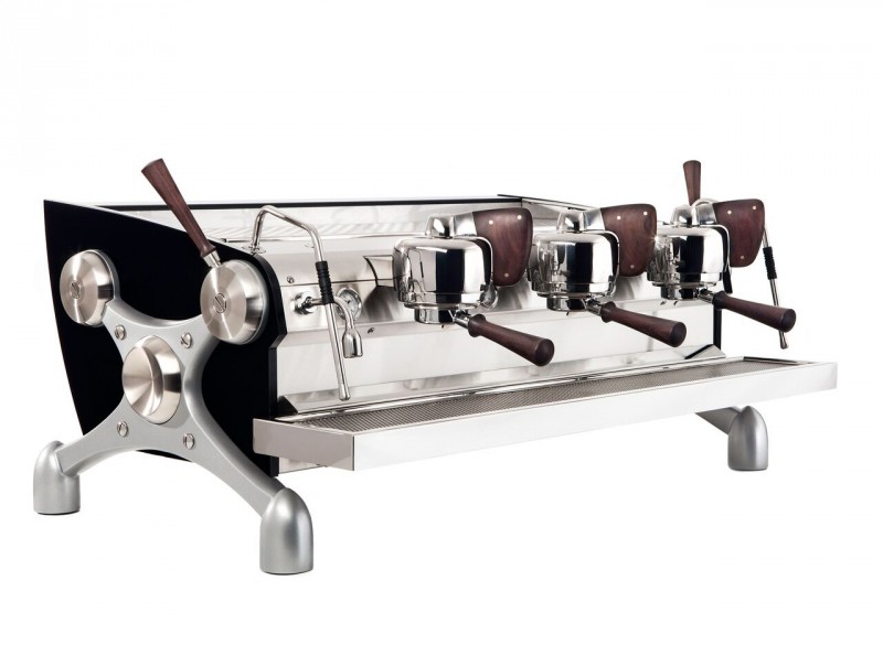 This image is a front-side view of the Slayer Espress machine powder coated black with peruvian walnut accents, 3 groups at traditional height and manual dosing controls.